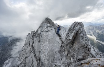 Mountaineer on a narrow rocky ridge on a steel cable, Watzmann crossing to Watzmann Mittelspitze,