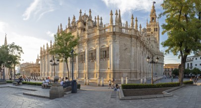 Lively square with cathedral in the background, benches and pedestrians, Seville