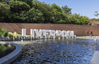 Large LIVERPOOL lettering in front of a watercourse and green surroundings, Liverpool