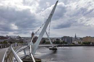 A deserted bridge over a tranquil river with dramatic clouds in the sky, Londonderry