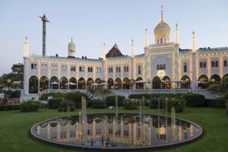 Illuminated Nimb restaurant reflected in pond, oriental architecture, Tivoli amusement and