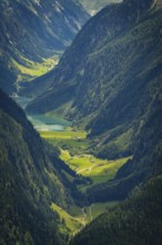 View of a sloping valley with a river, surrounded by green forests and high mountains, Stilluptal,