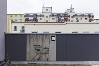 Shopping trolley with bricks instead of wheels, only preserved mural on a freshly painted wall,