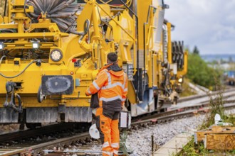 Construction worker working on a track with large yellow machines, track construction Hermann Hesse