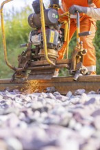 Worker using machine for track work, sparks flying, focus on outdoor activity, rail welding, track