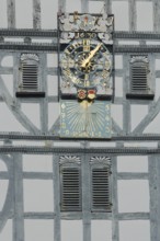 Golden clock with grey half-timbering and shutters, sundial, half-timbered house, wooden beams,