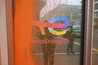 Company logo on the Total Energies building after the Last Generation colour attack. The police are