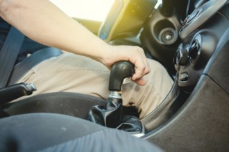 Close-up of driver hand on the gear lever of a car, Driver hand grabbing car gear stick, closeup of