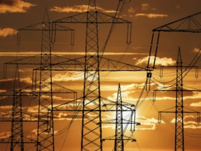 The pylon of a high-voltage power line in front of a sunset, Lower Saxony, Federal Republic of