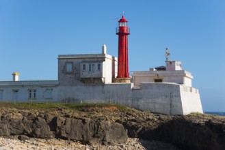 Close-up of a lighthouse on a rocky coast under a blue sky, Farol do Cabo Raso, São Brás de Sanxete