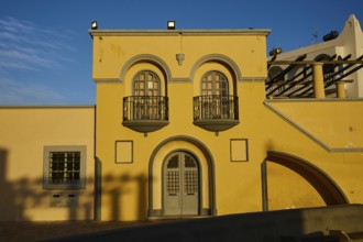 Yellow building with decorative balconies and large windows, illuminated by the last evening light,