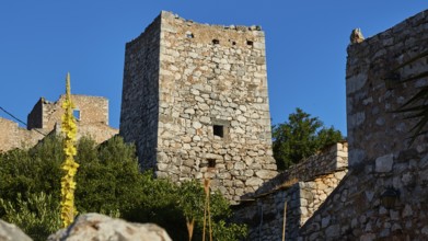 Medieval stone towers surrounded by Mediterranean vegetation under a blue sky, Lagia, residential