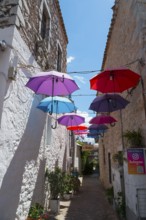 Narrow alley decorated with a row of colourful floating umbrellas, Old Town, Areopoli, Areopolis,