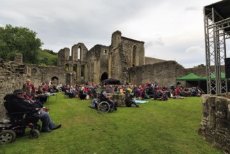 Visitors at an open-air concert in the evening, ruin, Abbey Farm, Llangollen, North Wales, Wales,