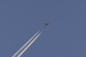 Boeing 787-8 Dreamliner aircraft flying across a blue sky with a vapour trail or contrail behind,