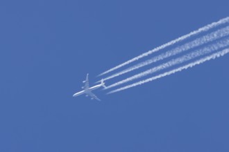 Airbus A340 aircraft flying across a blue sky leaving a contrail or vapor trail in the atmosphere