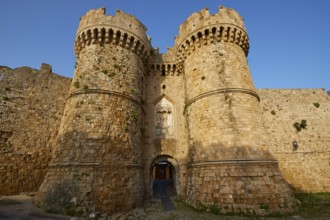 Stone castle wall with two towers and battlements in daylight, sea gate, harbour area, Rhodes Town,