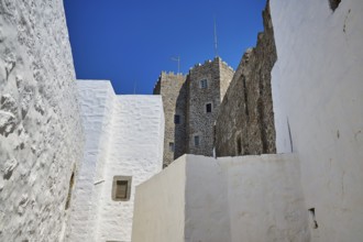 Medieval tower and white buildings with windows under a blue sky, Chora, Old Town, Patmos,