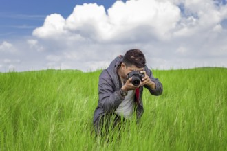 Man taking picture with camera in the field, photographer in the field taking a picture, Latino man