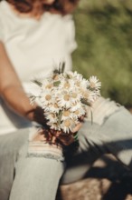 Woman holding a bouquet of daisy buds in a summer setting