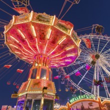 A funfair at dusk with illuminated chain carousel and Ferris wheel, Europa Rad, rides, wave flight,