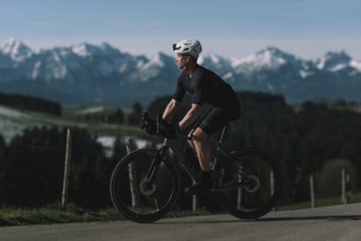 Road bike rider in spring in the Allgäu against the picturesque backdrop of the Alps, Bavaria,