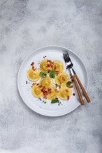 Fresh ravioli, with butter, spices and herbs, fried bacon, on the table, top view, light