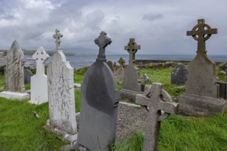 Coast with old gravestones against a cloudy sky and sea background, cemetery near Ballinskelligs