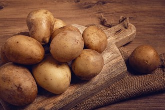 Raw potatoes, scattered on a chopping board, close-up, no people