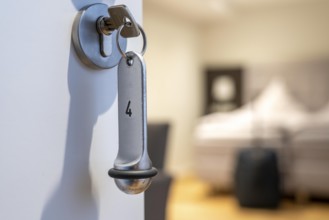 Symbolic image of a hotel, key inserted in the door of a hotel room, analogue lock