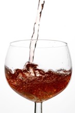 Orange-coloured liquid is poured into a wine glass, clear and elegant depiction