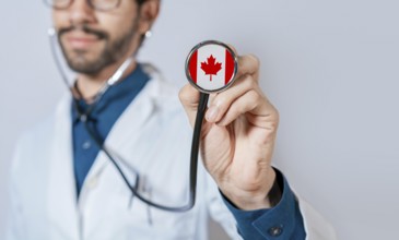 Doctor holding stethoscope with Canada flag. Canadian Health and Care Concept, Canada flag on