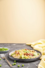 Quinoa porridge with green pea, corn and dried tomatoes on ceramic plate on a gray and orange