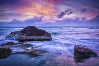 Tropical beach vacation background, waves and rocks on beach on sunset with beautiful cloudscape.