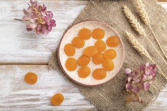 Jelly pumpkin candies on white wooden background and linen textile. close up, top view, flat lay.