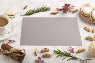 Gray paper sheet mockup with cup of coffee, almonds and macaroons on gray concrete background.