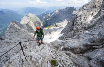 Mountaineer with helmet in a secured via ferrata, Zugspitze via ferrata, ascent to the Zugspitze,