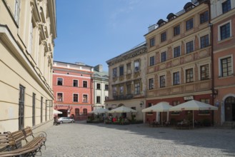 Cobbled old town alleyway with historic buildings and sunlight, benches at the roadside, Old Town