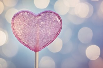 Pink heart shaped Valentine's Day lolli in front of background with bokeh lights. Generative AI, AI