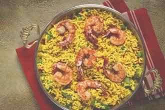 Rice with saffron and shrimp, in a frying pan, paella with shrimp, top view, homemade, no people