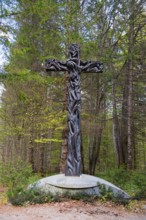 Wooden cross in a forest, surrounded by trees, symbolising Christian themes and peace, Jama pod