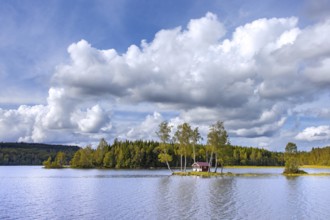 Small traditional red wooden cabin on tiny island in lake in autumn, fall, Värmland, west-central