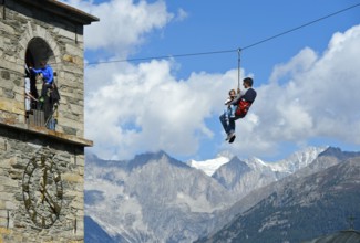 Father and his daughter glide down a zip wire from the church tower to the ground,