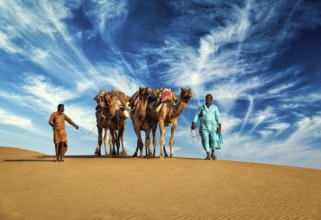 Rajasthan travel background, two Indian cameleers (camel drivers) with camels in dunes of Thar