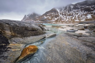 Rocky coast of fjord of Norwegian sea in winter with snow. Haukland beach, Lofoten islands, Norway,