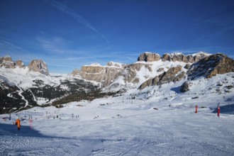 View of a ski resort piste with people skiing in Dolomites in Italy. Ski area Belvedere. Canazei,