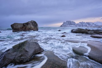 Rocks on beach of fjord of Norwegian sea in winteron sunset. Utakliev beach, Lofoten islands,