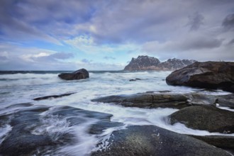 Rocks on beach of fjord of Norwegian sea in winter with snow. Utakliev beach, Lofoten islands,