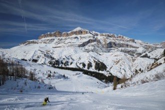 View of a ski resort piste with people skiing in Dolomites in Italy. Ski area Arabba. Arabba,