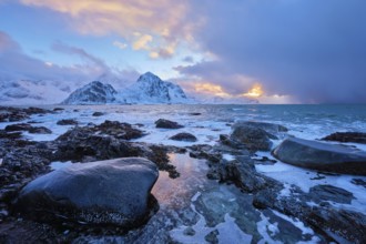 Beach of Norwegian sea on rocky coast in fjord on sunset in winter. Vareid beach, Lofoten islands,